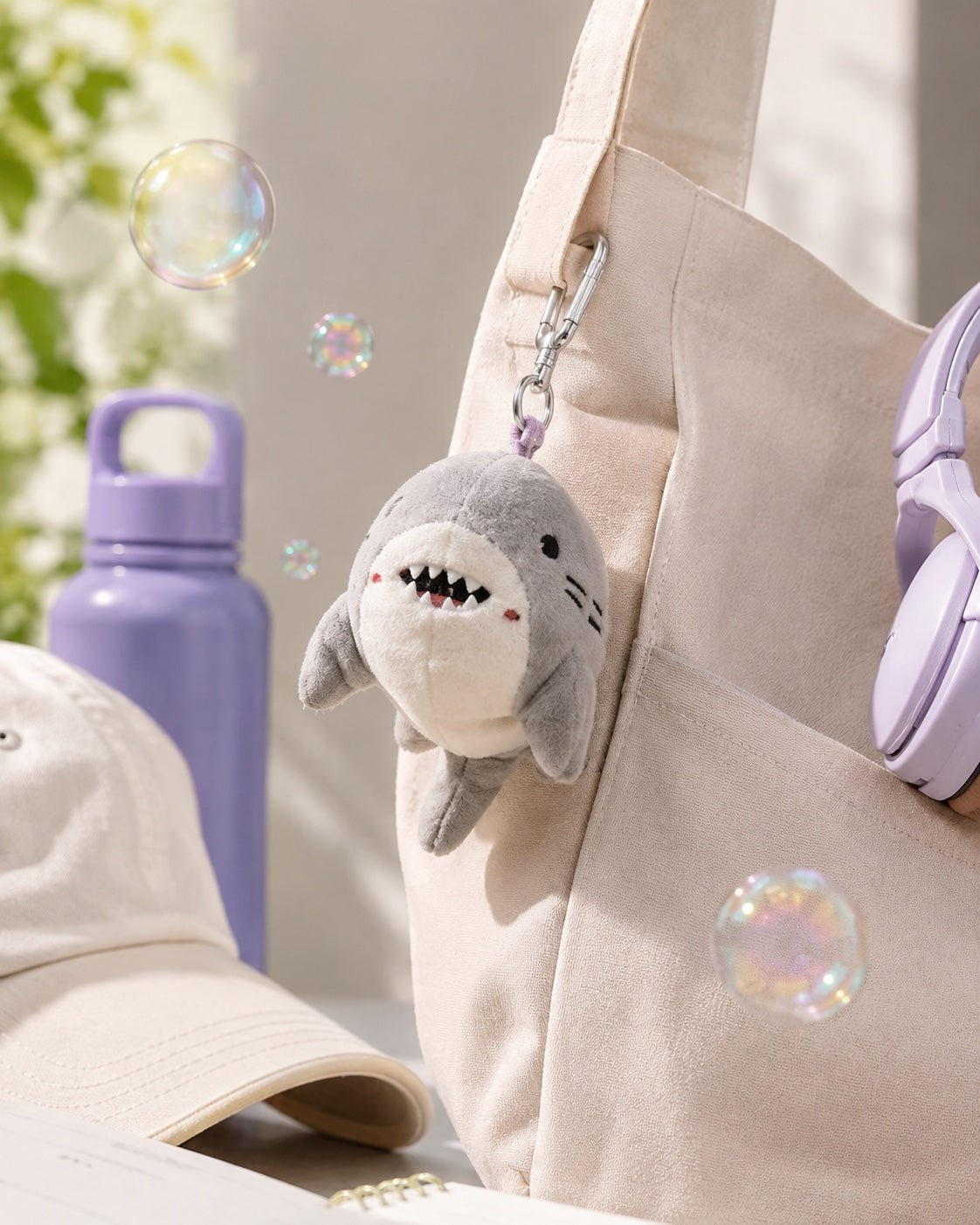 Grey shark plush bag charm clipped to a cream tote